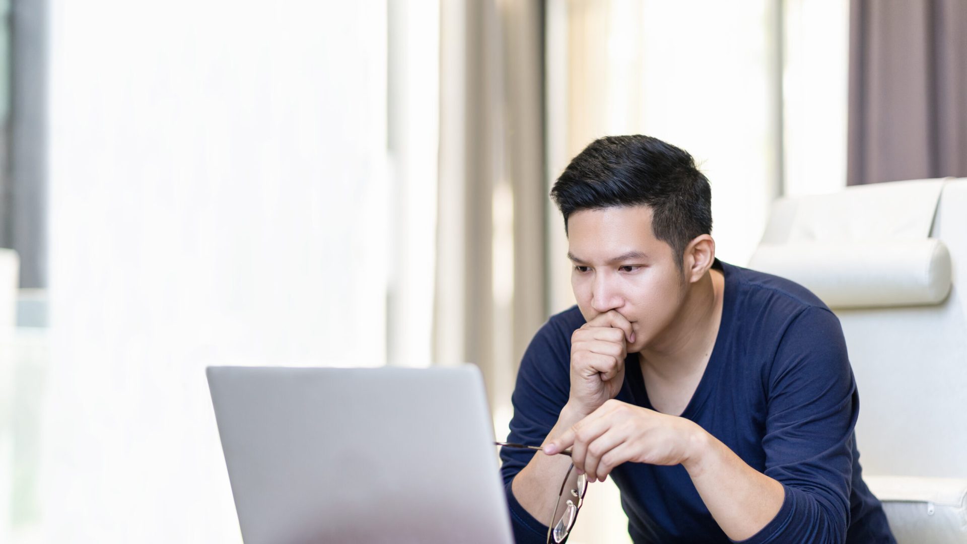 seriously confident asian young freelancer in smart casual working and concentrated on laptop sitting on desk in modern office ,co-working space or at home with copy space, webinar over the internet