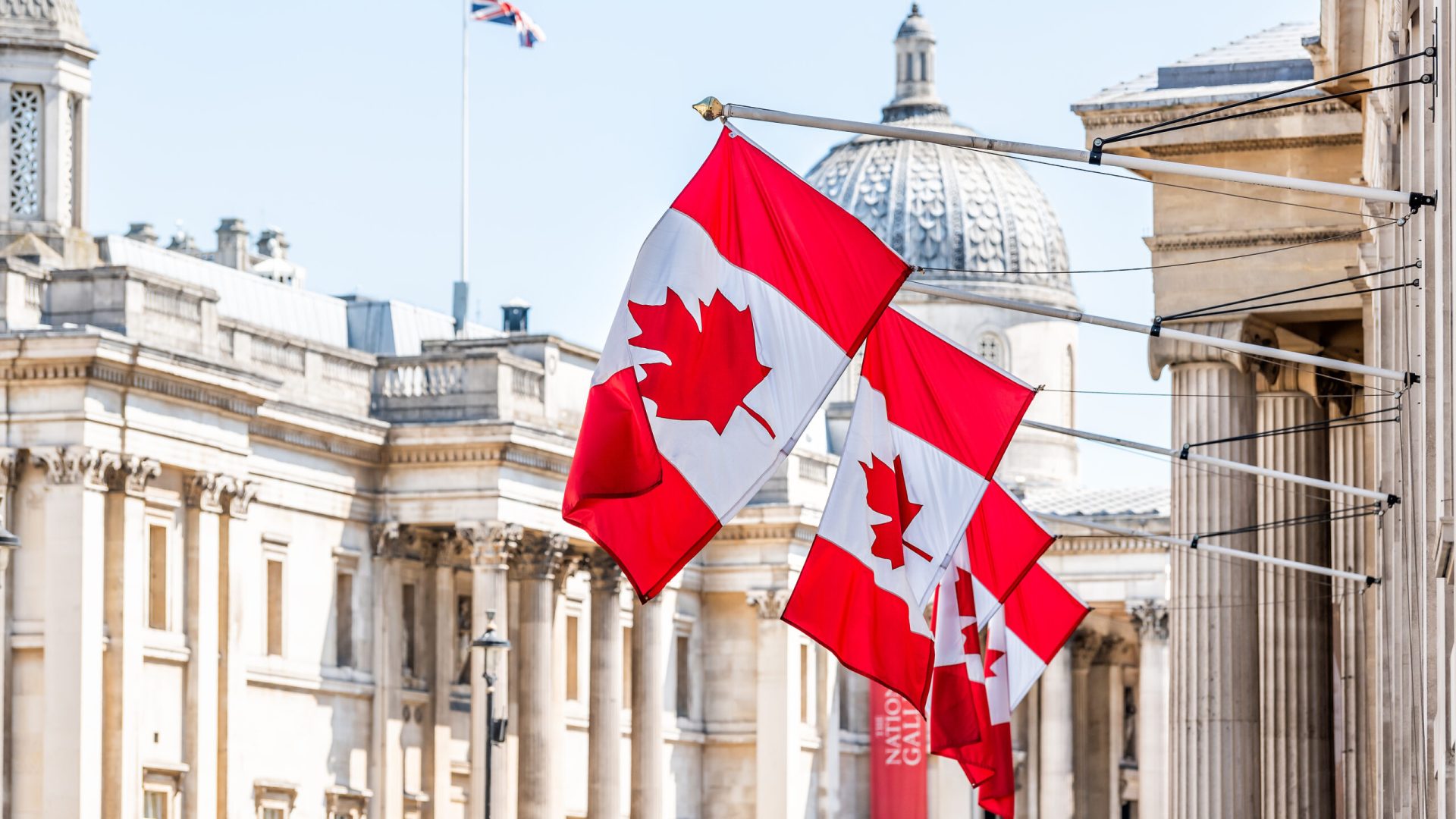 London, UK High Commission of Canada with closeup of row of red colorful Canadian flags on Cockspur Street in Westminster