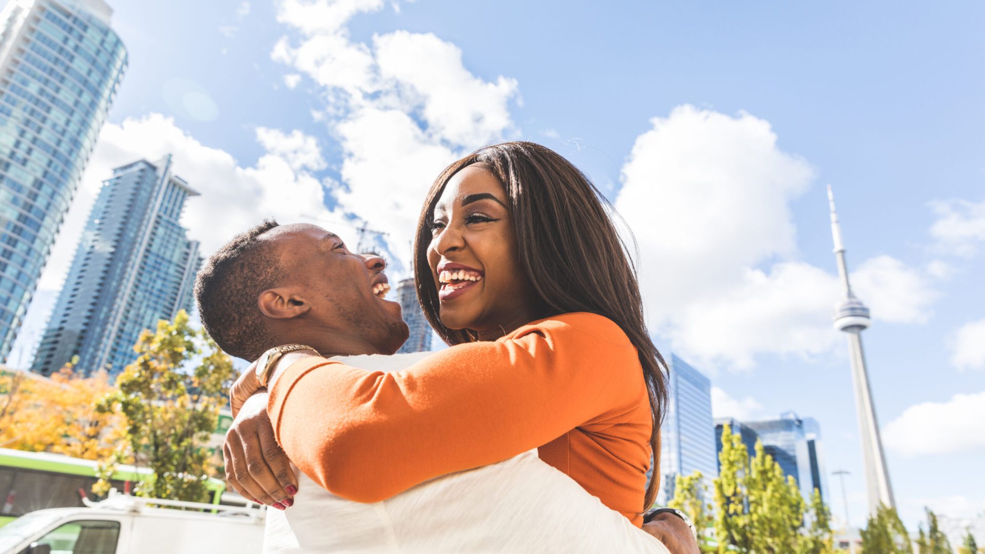 Happy black couple having fun in Toronto - Man and woman embracing and laughing in the city during the day - Lifestyle and friendship or love concepts