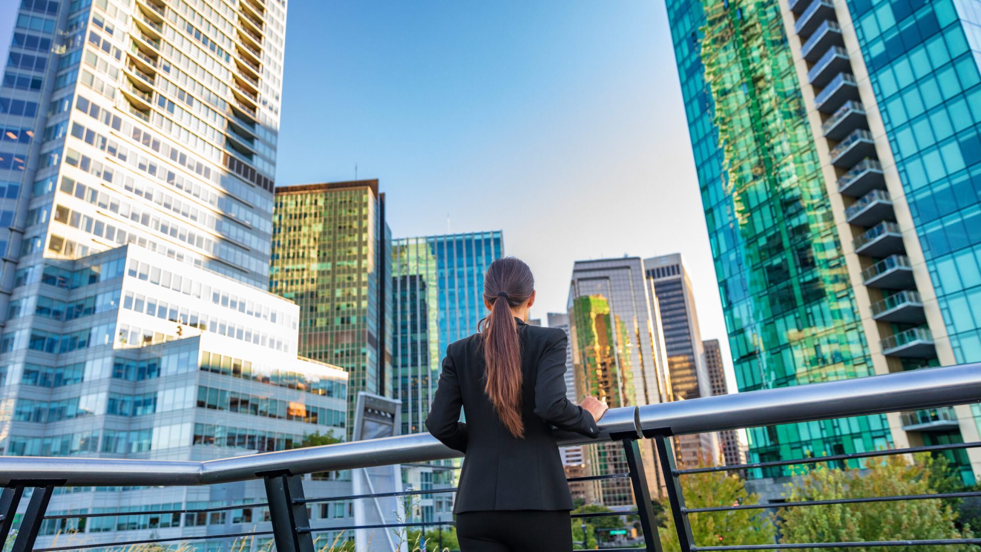 Business woman in city center looking at view of skyline skyscrapers in Vancouver downtown , Canada. Businesswoman from the back pensive thinking about success and future in career and job.