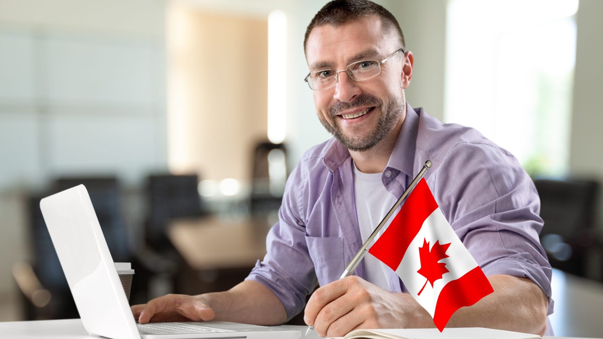 Young business man at work with flag of Canada .