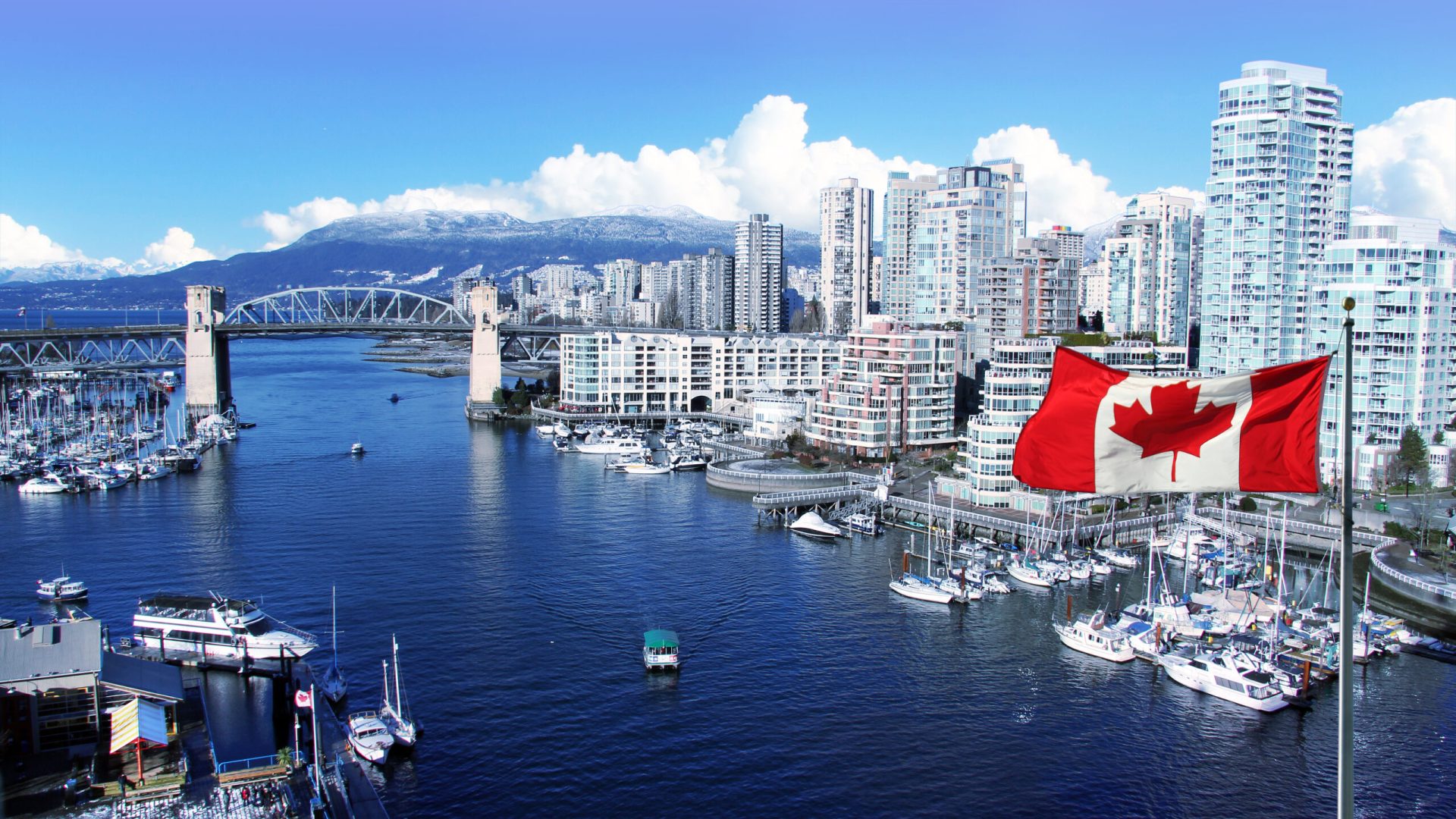 Canadian flag in front of view of False Creek and the Burrard street bridge in Vancouver, Canada.